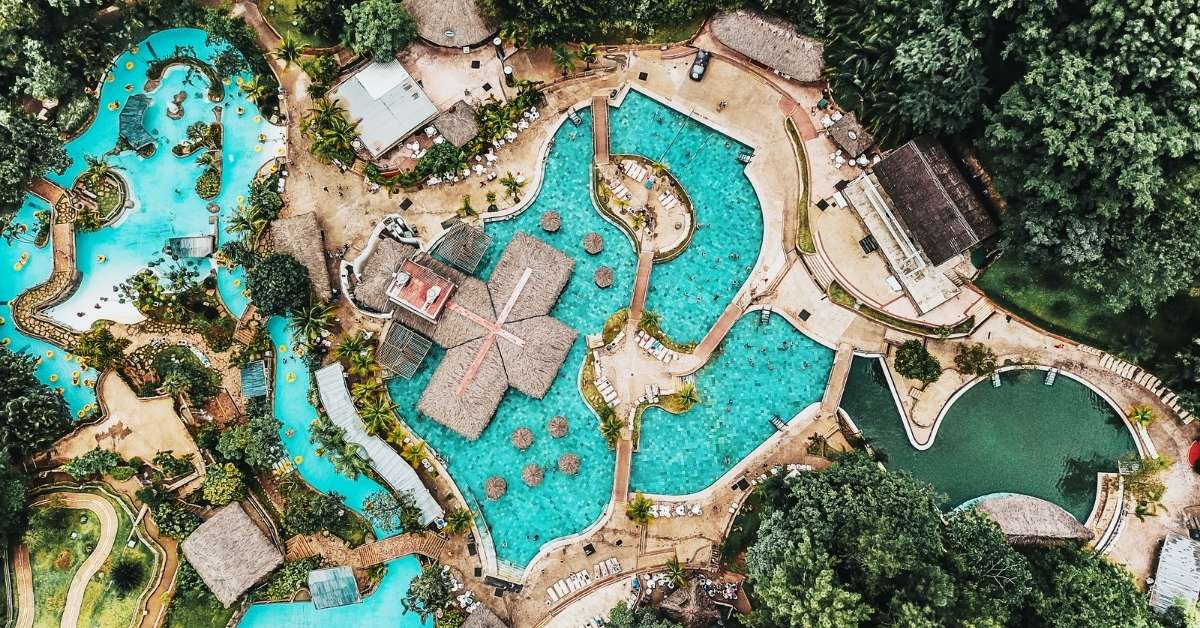 Aerial view of a tropical resort featuring elaborate and luxurious interlinking blue pools
