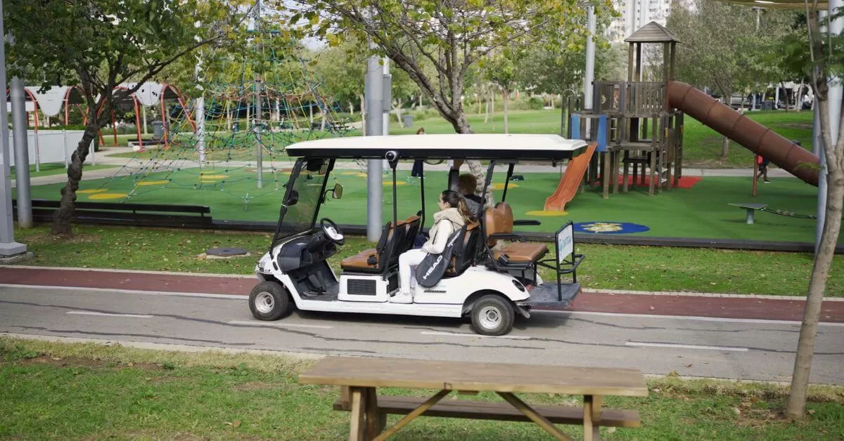 a couple riding through a park in an autonomous golf cart